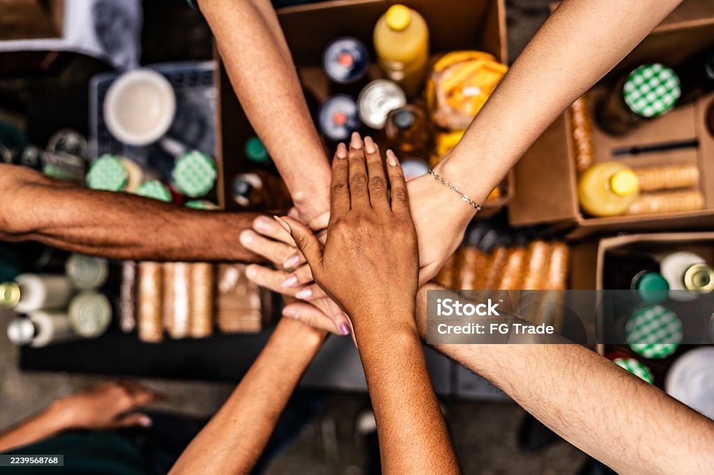 Diverse group placing hands together in the center to symbolize teamwork and unity.